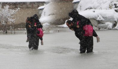 Evinin önünde biriken su nedeniyle çocuklarını sırtında taşıyor