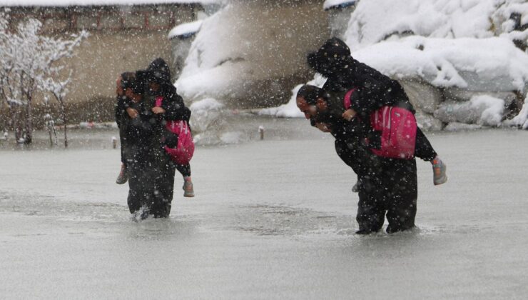 Evinin önünde biriken su nedeniyle çocuklarını sırtında taşıyor